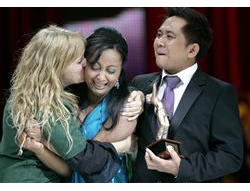 Natércia Pintor embraces her translator, Carolina Alves, after being named the new “Voice of McDonald’s®” as Candido Revilles, who placed third, looks on.